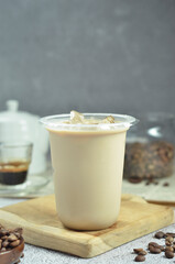 Ice coffee in a plastic cup with brown sugar and ice cubes and beans