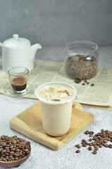 Ice coffee in a plastic cup with brown sugar and ice cubes and beans