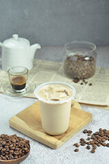 Ice coffee in a plastic cup with brown sugar and ice cubes and beans