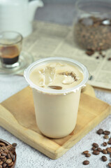 Ice coffee in a plastic cup with brown sugar and ice cubes and beans