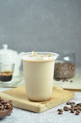 Ice coffee in a plastic cup with brown sugar and ice cubes and beans