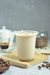 Ice coffee in a plastic cup with brown sugar and ice cubes and beans