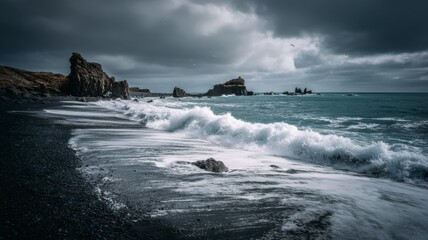Rough waves roll onto a dark sandy beach while clouds gather above in a dramatic coastal setting.
