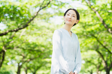 並木で見上げている若い女性　ライフスタイルイメージ