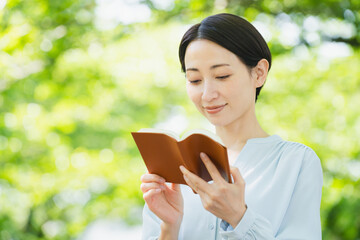 Fototapeta premium 屋外で読書をする若い女性 ライフスタイルイメージ