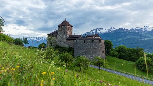 Day to Night Timelapse of Vaduz Castle in Lichtenstein with the alps behind and car passing by
