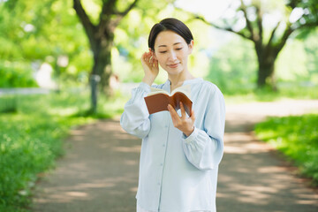 Fototapeta premium 屋外で読書をする若い女性 ライフスタイルイメージ
