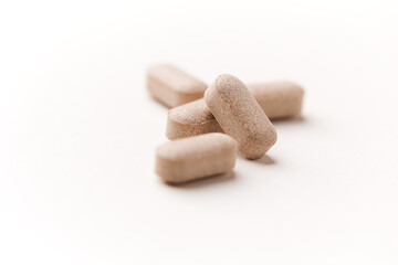 Lion’s mane mushrooms tablets that have beneficial effects on the body, especially the brain, heart, and intestines. Bright paper background. Soft focus. Close up. Copy space.	