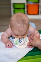 Baby boy celebrating six months milestone with decorative sign