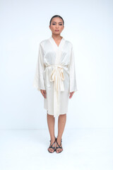 An empowered young asian woman standing tall in a luxurious silk robe, radiating elegance and...