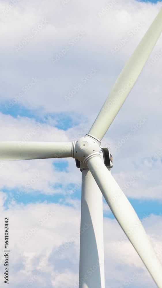 Poster a dynamic vertical video showing a close-up of wind turbine blades rotating under a vibrant sky with