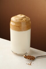 Delicious dalgona coffee in glass and granules on white table