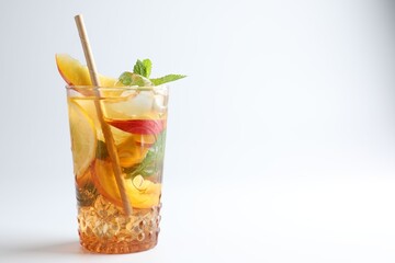 Tasty iced tea with lemon, peach and mint on white background, closeup. Space for text