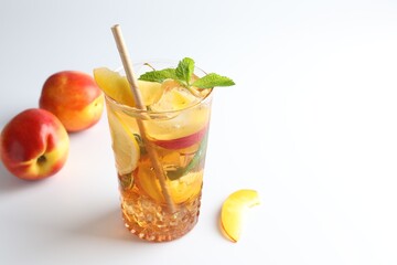Tasty iced tea with lemon, peaches and mint on white background, closeup. Space for text