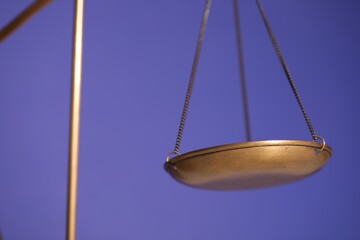 Scales of justice on violet background, closeup
