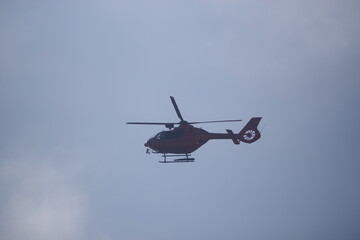 Red helicopter is flying in the sky