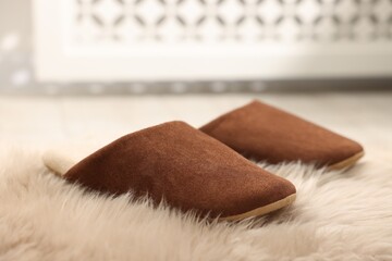 Stylish brown slippers on fluffy carpet indoors, closeup