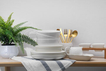 Different clean white dishware and cutlery on wooden table indoors