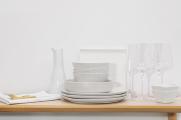 Different clean white dishware, glasses and cutlery on wooden table indoors