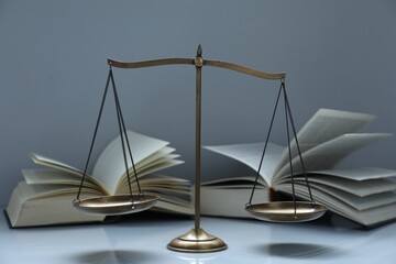 Scales of justice and books on grey background