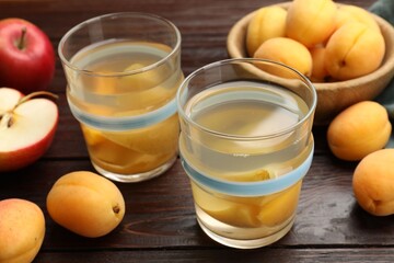 Tasty compot and fruits on wooden table, closeup