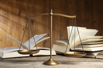 Scales of justice and books on wooden table