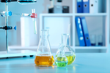 Laboratory glassware with different samples on table indoors. Solution chemistry