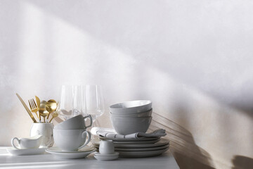 Different clean white dishware and glasses on counter in kitchen, space for text