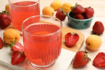 Tasty compot in glasses, fresh strawberries and apricots on wooden table, closeup