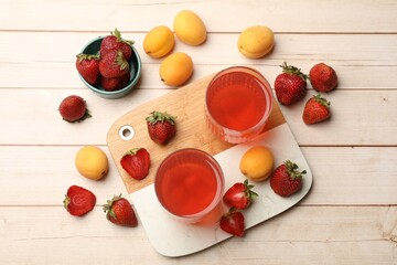 Tasty compot in glasses, fresh strawberries and apricots on wooden table, flat lay