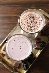 Different tasty milkshakes in glasses and ingredients on wooden table, top view