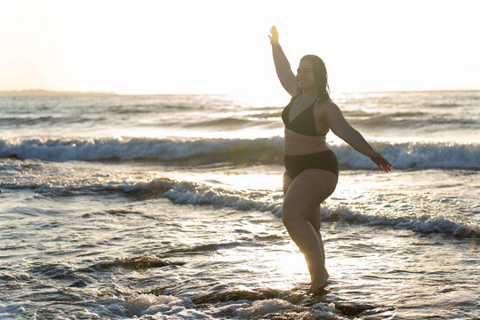 Curvy woman enjoying sunset at the beach, embracing body positivity