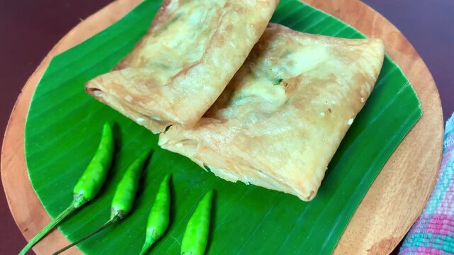 4K footage of crispy Indonesian martabak telor with fresh green chilies on banana leaf, top view. Perfect for food, culture, recipe, street food, and culinary themes.
