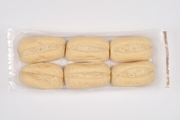 Six white bread rolls are packaged in clear plastic wrap on a neutral light gray background