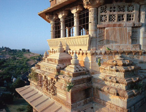 Aerial view of the carved sandstone of the Jahangir Mahal, bathed in soft morning light, contrasts with the distant green hills, Orchha, Madhya Pradesh, India.
