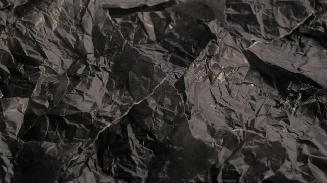 wrinkled and ripped black paper. Crumpled and torn black paper texture with intricate details and shadows for creative design projects and backgrounds 