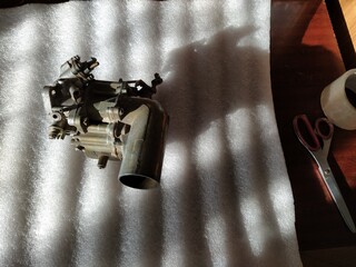 Old carburetor for a car engine with tools on table