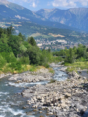 Torrent Vach&egrave;res &agrave; Baratier avec la ville d'Embrun &agrave; l'horizon, Hautes-Alpes, France