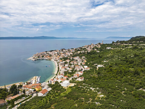 Aerial view of the terracotta rooftops cascading down to the turquoise Adriatic Sea in Igrane, fringed by verdant hillsides, Split-Dalmatia County, Croatia.