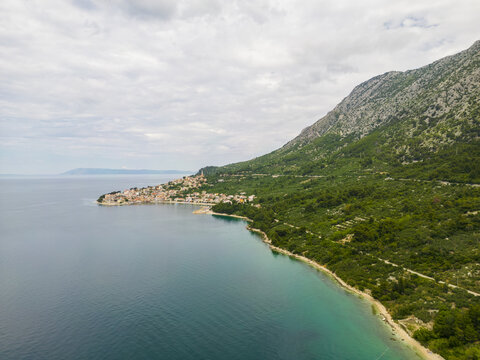Aerial view of the coastline where the turquoise sea meets the rugged, forest-covered mountain near the charming village, Igrane, Split-Dalmatia County, Croatia.