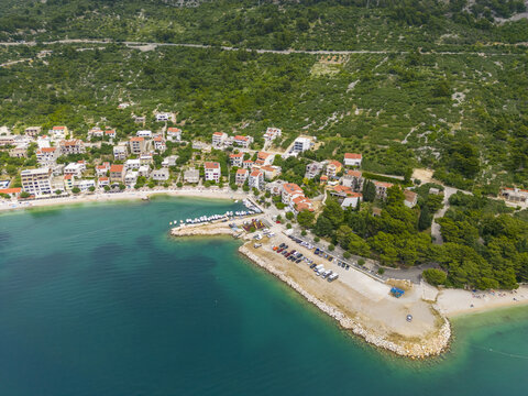 Aerial view of the vibrant coastal village nestled between the turquoise Adriatic Sea and the lush green mountains, Igrane, Split-Dalmatia County, Croatia.