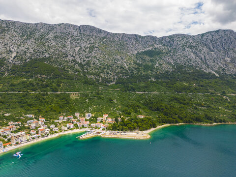 Aerial view of the vibrant coastal village nestles against the majestic mountain range, where terracotta roofs meet the azure sea, Igrane, Split-Dalmatia County, Croatia.