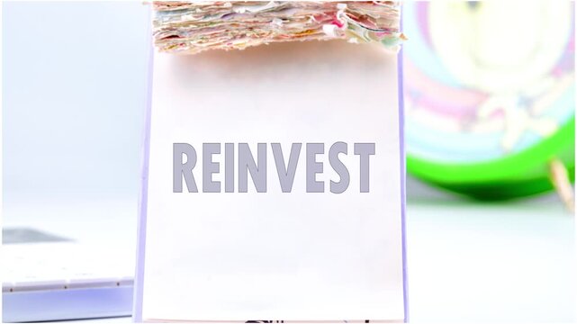The text of REINVEST appears on the desktop calendar , Animation of the word REINVEST. Reinvest symbol. Business and reinvest concept.