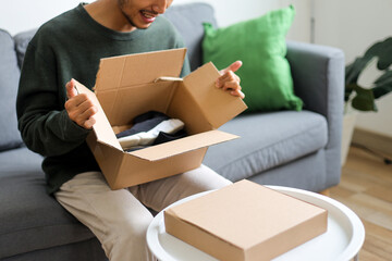 Male Influencer Sitting On Sofa Enthusiastically Talking About Product From Cardboard Box
