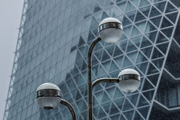 Lamps resembling sci-fi alien heads affixed to long necks sit against contemporary building...