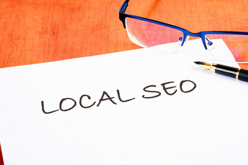 LOCAL SEO text written on a white piece of paper on the table next to the glasses