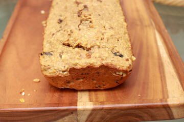 Homemade oatmeal bread with nuts and raisins displayed on a wooden board 