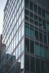 Obraz premium A dynamic low-angle shot of a modern glass and steel skyscraper, highlighting the sleek lines and reflective surfaces of contemporary urban corporate architecture. 