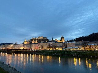 Salzburg at Dusk with Festive Christmas Market Lights Along the River
