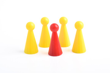 Red board game figure among yellow ones on white background. Difference, individuality, uniqueness